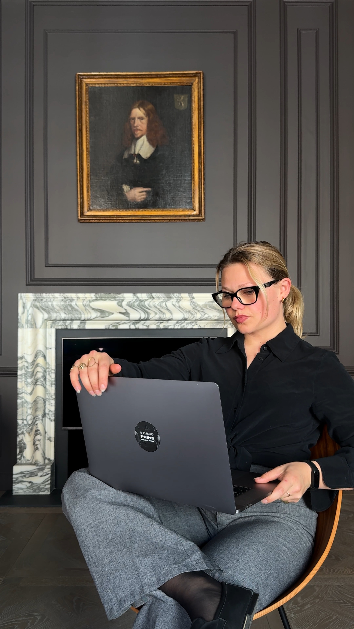 Emma seated with her laptop in front of a marble fireplace