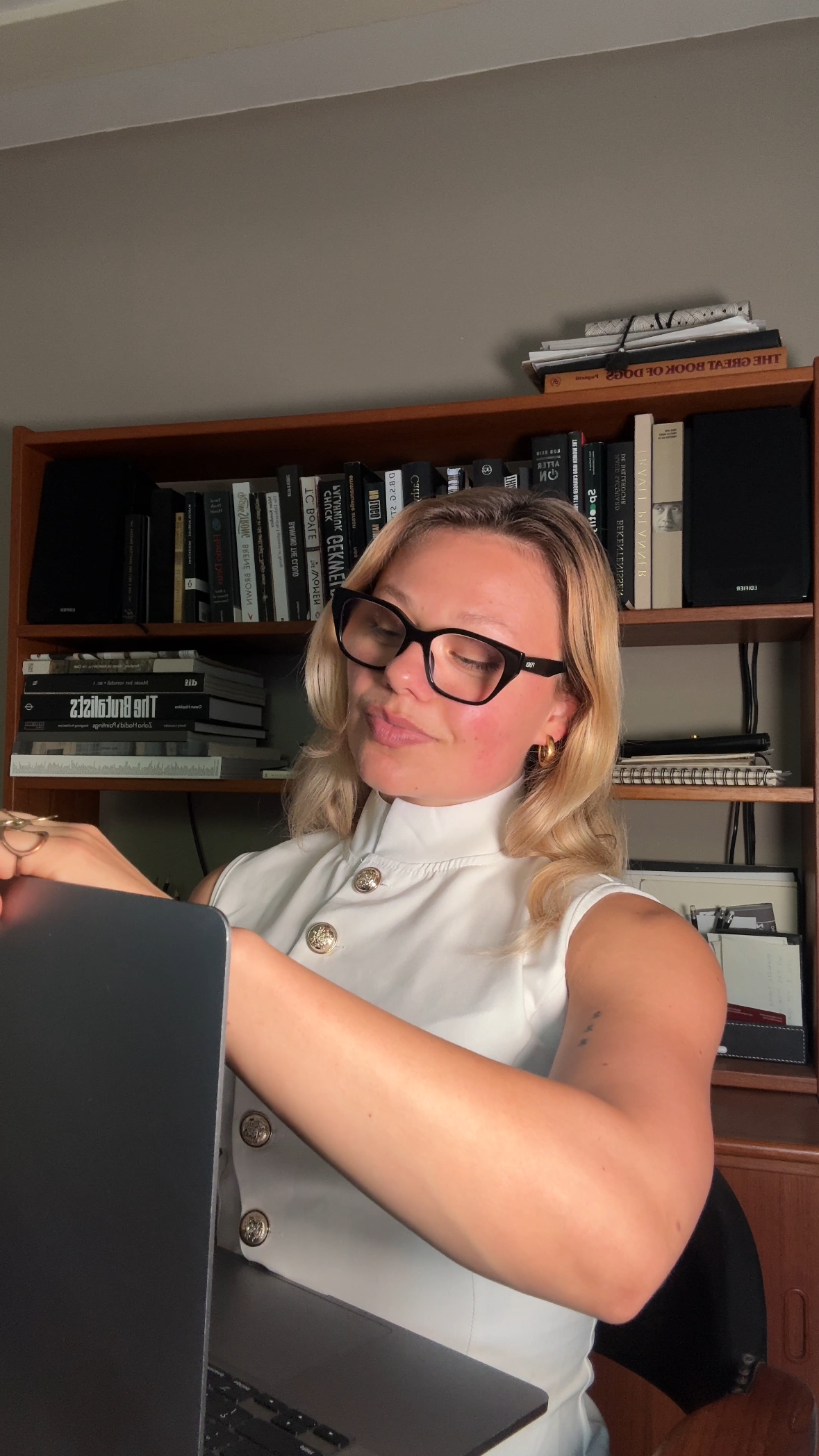 Emma at her desk in front of a bookshelf, laptop half closed