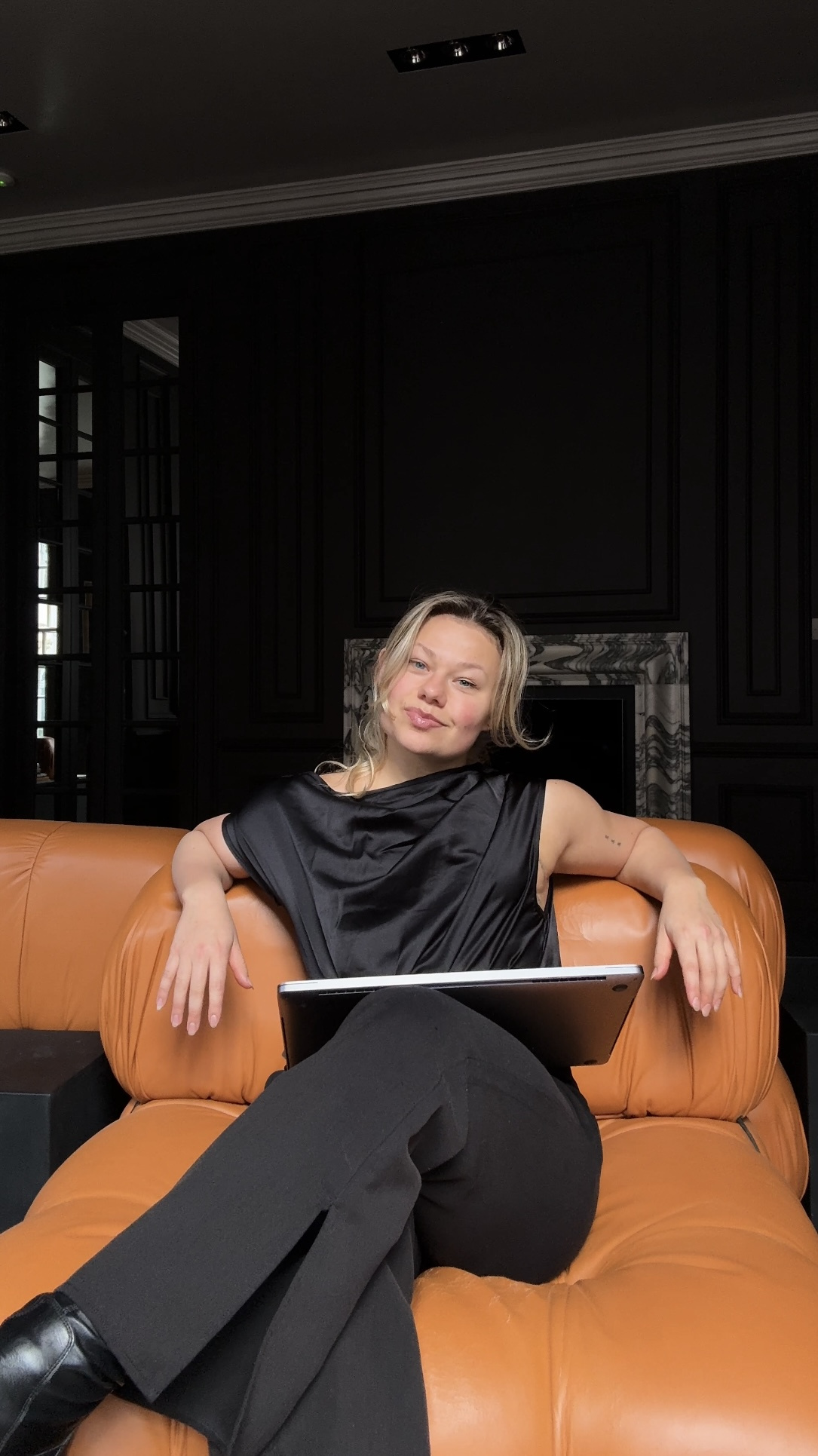 Emma relaxing on an orange leather sofa with her laptop